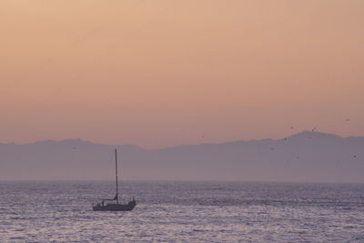 Silhouette sailboat in sea against sky during sunset