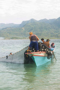 People in boat on sea against mountains