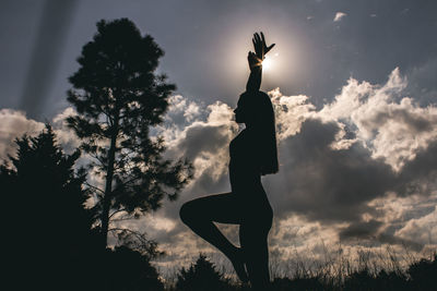 Silhouette woman standing by tree against sky during sunset