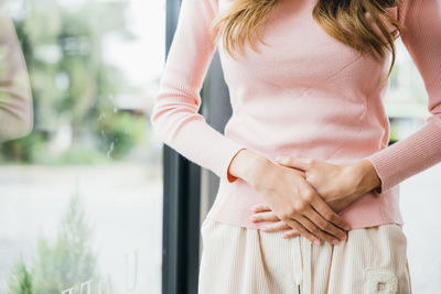 Midsection of woman standing against window