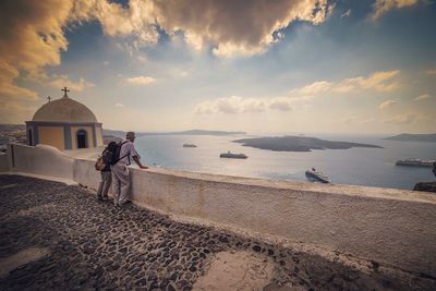 People by sea against cloudy sky at santorini island