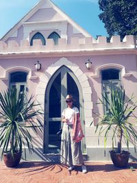 Woman standing against building during sunny day