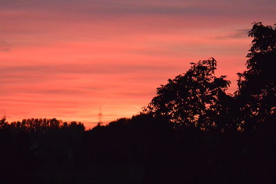 Silhouette trees against dramatic sky during sunset