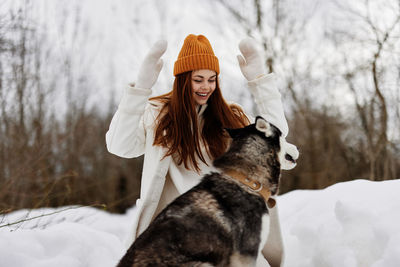 Portrait of young woman with dog on snow covered field