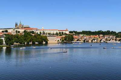 Scenic view of river by buildings against clear blue sky