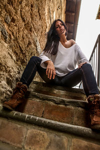 Portrait of young woman sitting on wall