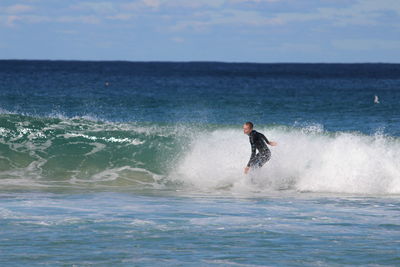 Man surfing in sea against sky