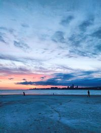 Scenic view of beach against sky at sunset