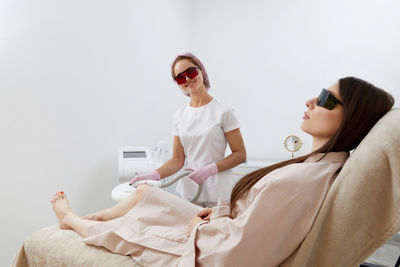 Young woman wearing sunglasses while sitting on bed