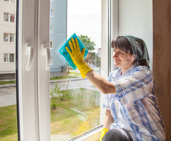 Woman cleaning glass window at home