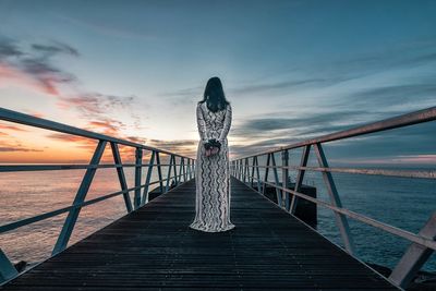 Pier over sea against sky during sunset