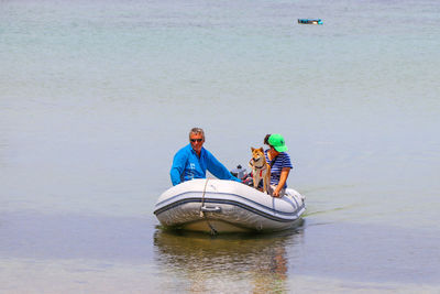 Friends with dog on inflatable raft over sea