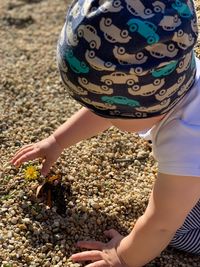 High angle view of boy holding flower in pebble stones