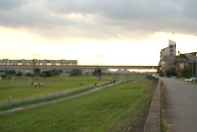 Road amidst field against sky during sunset