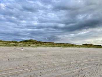 Scenic view of beach against cloudy sky