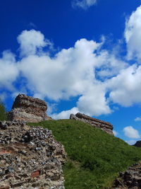 Low angle view of old ruins on hill against sky