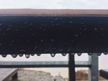 Close-up of wet metal against sky