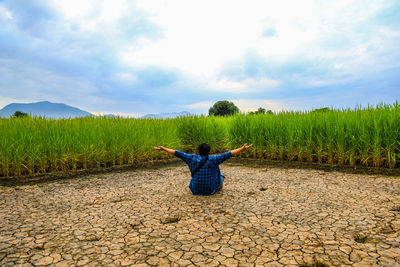 Woman with umbrella on field against sky