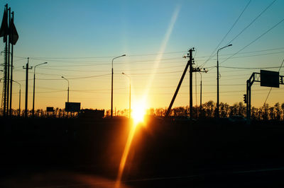 Silhouette electricity pylon against sky during sunset