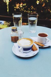 Glass of water and coffee cups on table outdoors 