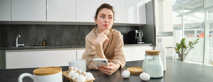 Portrait of young woman using mobile phone at home