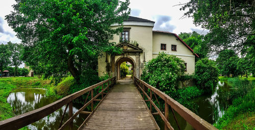 Footbridge amidst trees and plants against sky