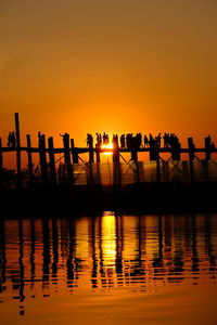 Silhouette people against orange sky during sunset