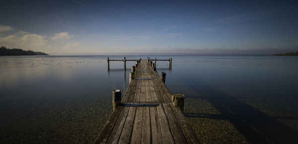 Wooden pier on sea against sky