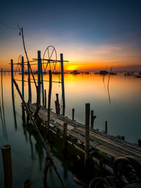 Pier over sea against sky during sunset