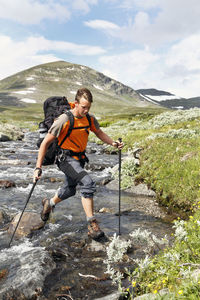 Hiker crossing mountain river