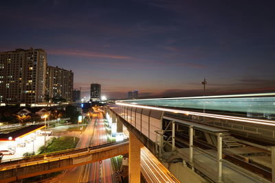 Light trails on road amidst buildings in city at night