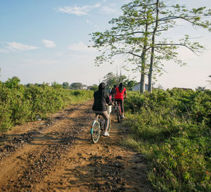 Girl riding bicycle on road against sky