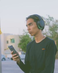 Young man using mobile phone against sky