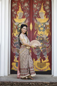 Portrait of young woman standing by door