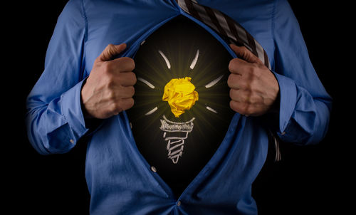 Midsection of man showing symbol against black background