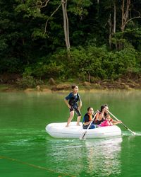 Rear view of women on boat against trees