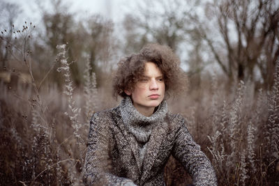 Boy looking away sitting amidst plants outdoors