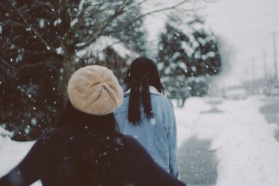 Rear view of woman on snow covered trees in city