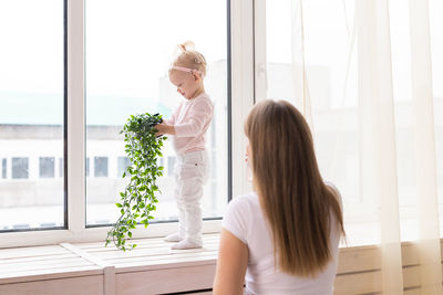 Side view of woman looking through window