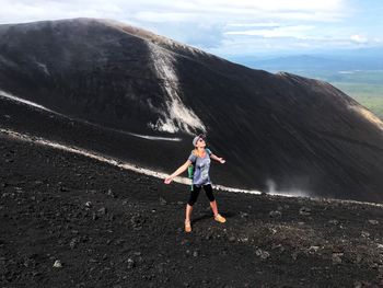 Full length of mature woman with backpack on mountain against sky