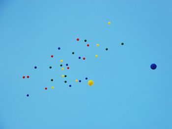 Low angle view of colorful balloons flying against clear blue sky