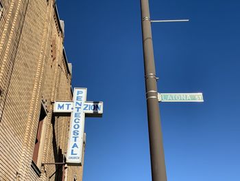 Low angle view of sign against clear blue sky