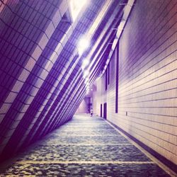 Empty walkway in illuminated corridor