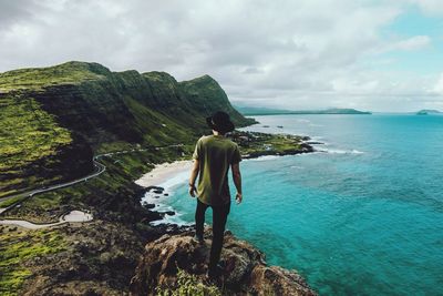 Rear view of man on cliff by sea