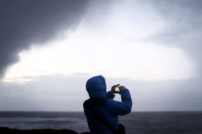 Rear view of person photographing sea