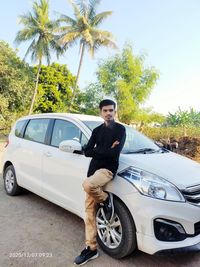 Full length portrait of young man standing in car