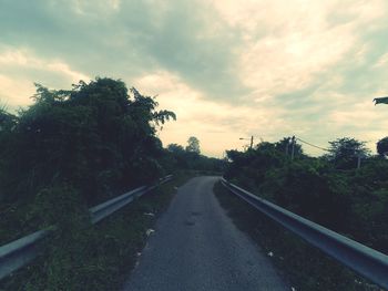 Road amidst trees against sky during sunset