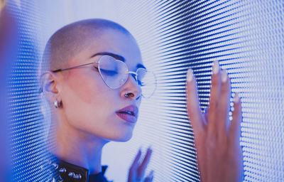 Close-up of young woman with shaved head standing against abstract backgrounds