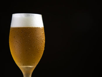Close-up of beer glass against black background