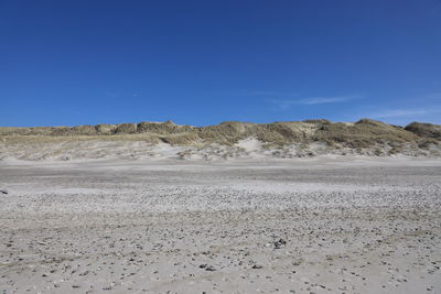 Scenic view of desert against clear blue sky